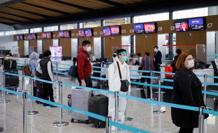 A passenger wearing a protective suit stands in a queue the Istanbul Airport during the first day of resumed domestic flights 