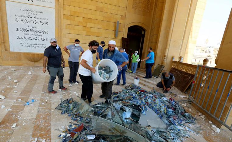 لبنانيون يحمعون زجاجا محطما بعد انفجار بيروت