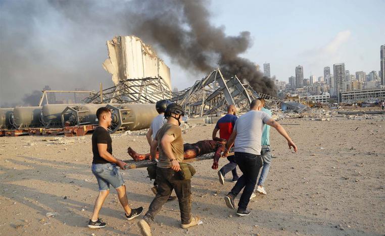 Civilians carry a person at the explosion scene that hit the seaport, in Beirut 