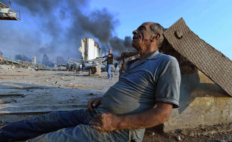 A wounded man sits on the ground waiting for aid at Beirut's port 
