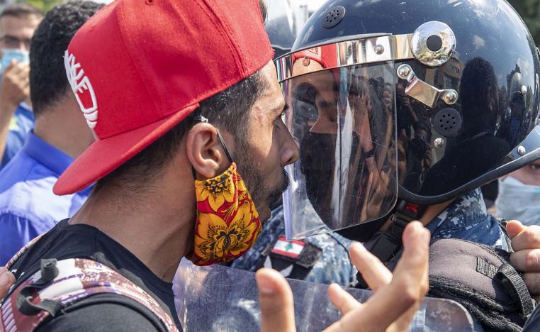 An anti-government protester faces riot police outside the Ministry of Energy and Water in Beirut