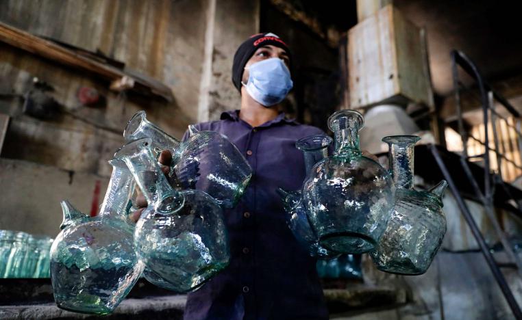 عامل يغسل أباريق في مصنع بطرابلس يقوم بإعادة تدوير الزجاج المكسور نتيجة انفجار بيروت 