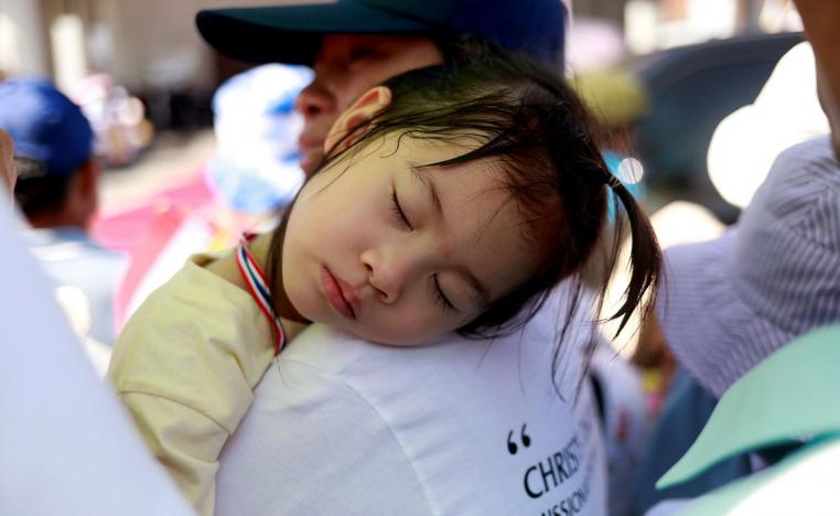 طفلة تايلاندية تنام على كتف والدها