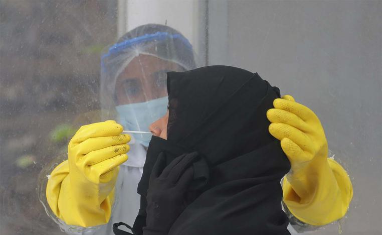 A health worker collects a nasal swab sample to test for COVID-19 in Hyderabad, India