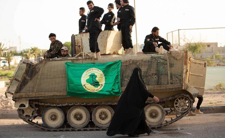 سيدة عراقية تمر بالقرب من عربة مصفحة للحشد الشعبي في البصرة