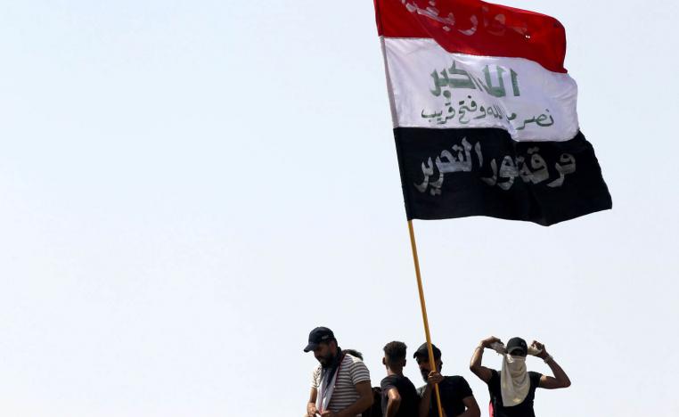 محتجون عراقيون يرفعون علم بلادهم في ساحة التحرير وسط بغداد