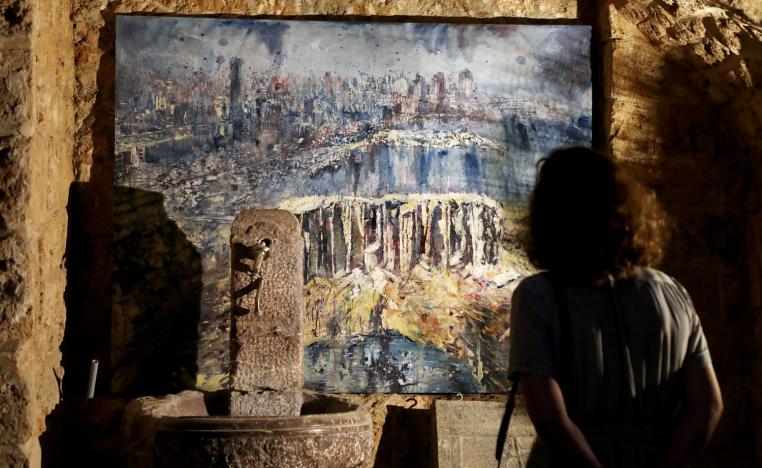 لبنانية تنظر إلى لوحة تصور مشهد الدمار في بيروت