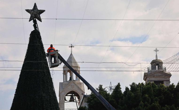 A worker sets up lights on a giant Christmas tree at the Church of the Nativity compound 