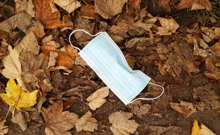 كمامة مستخدمة ملقاة بين الاشجار