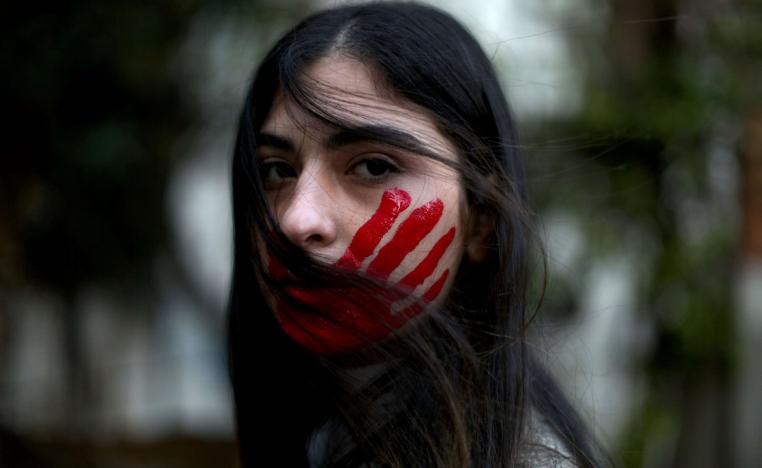 متظاهرة أميركية ضد العنف ضد المرأة ترسم ضربة كف على وجهها