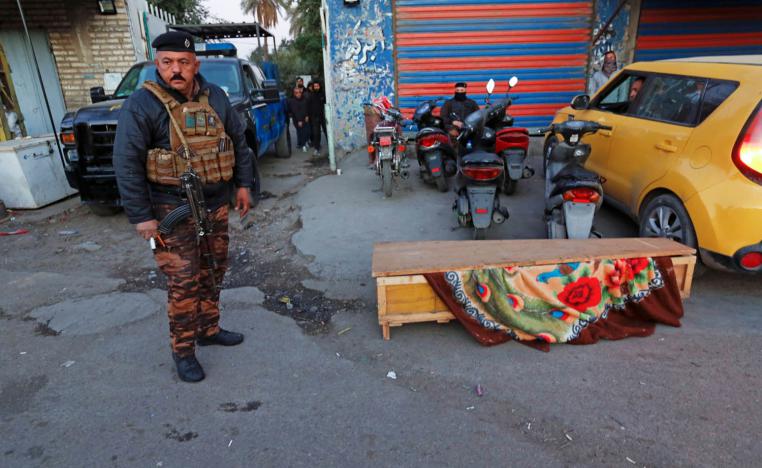 شرطي عراقي بجانب تابوت لضحية من ضحايا تفجير ساحة الطيران في بغداد
