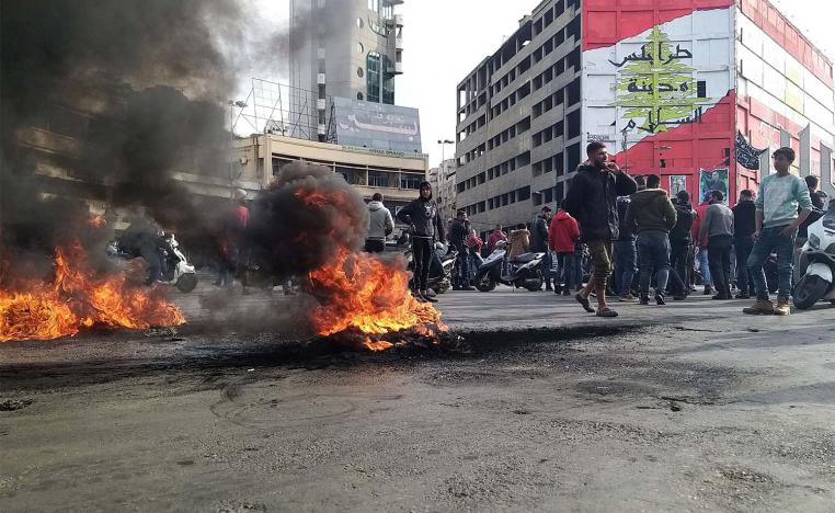 Demonstrators gather near burning tires during a protest against the lockdown and worsening economic conditions
