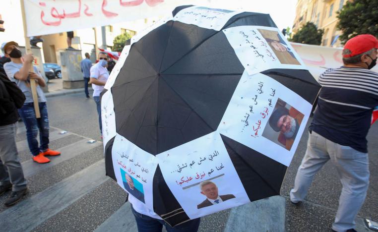 محتج لبناني في بيروت يستعرض صورا للطبقة السياسية الحاكمة