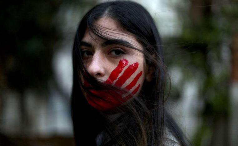 امرأة اميركية ترسم على وجهها ضربة كف بالاحمر احتجاجا على العنف ضد النساء