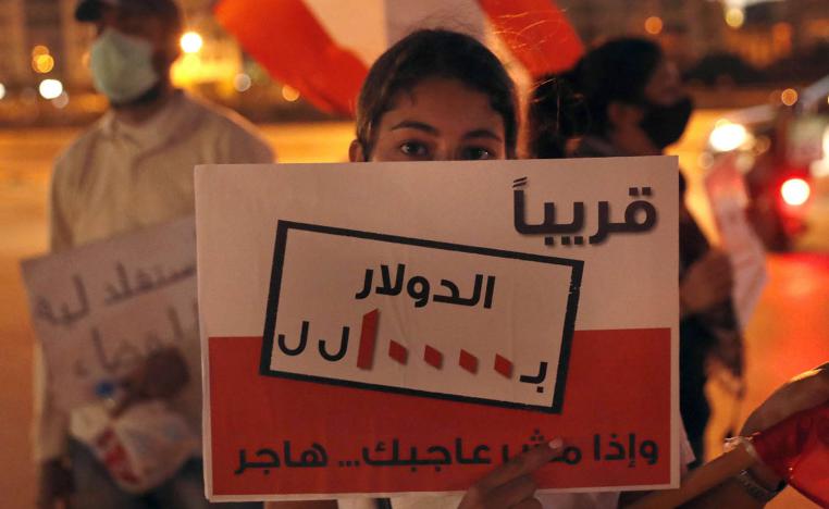 طفل لبناني يرفع لافتة تحذر من انهيار العملة