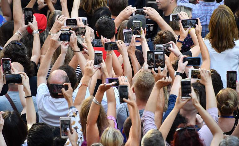 أشخاص يلتقطون صورًا ومقاطع فيديو بهواتفهم المحمولة خلال حفلة بنيويورك