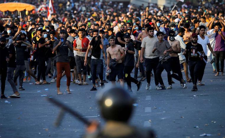 Demonstrators face security forces during an anti-government protest in Baghdad