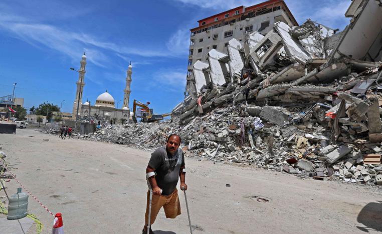 فلسطيني معوق يمر بجانب بناية دمرها القصف الإسرائيلي في غزة