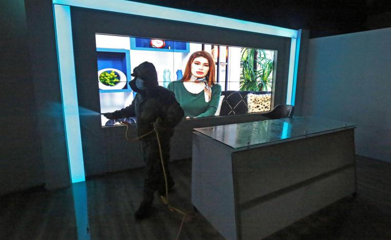 عامل صحي يقوم بتعقيم ستوديو لقناة في العراق