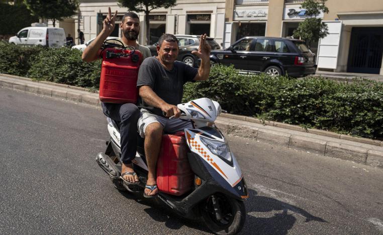 صيادان لبنانيان على دراجة نارية يحملان وقودا لقاربهما