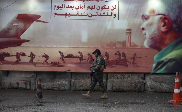 مقاتل من الحشد الشعبي أمام جدارية لأبو مهدي المهندس في بغداد