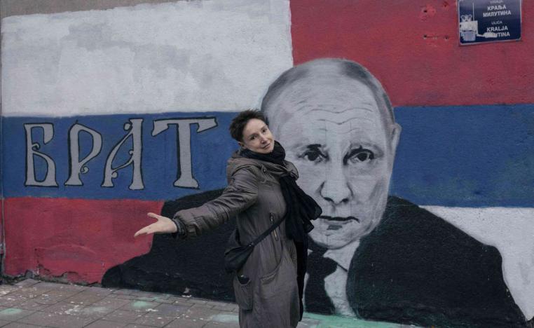 روسية أمام صورة لبوتين وسط بلغراد