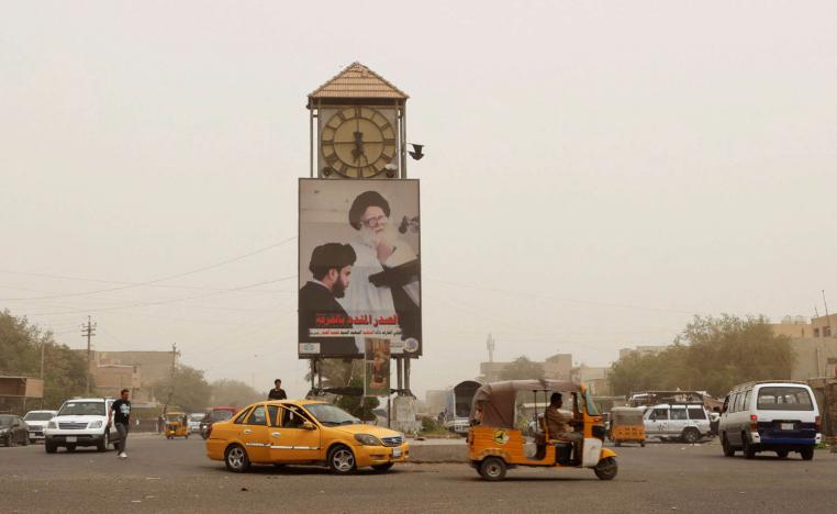 صورة لمقتدى الصدر ووالده تغطي ساعة في ساحة عامة ببغداد
