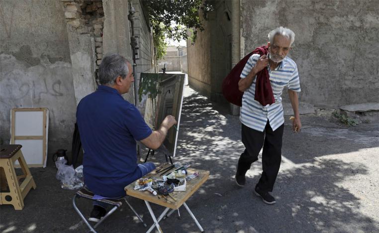 Painter Hassan Naderali paints an old building in the historic neighborhood of Oudlajan, in Tehran