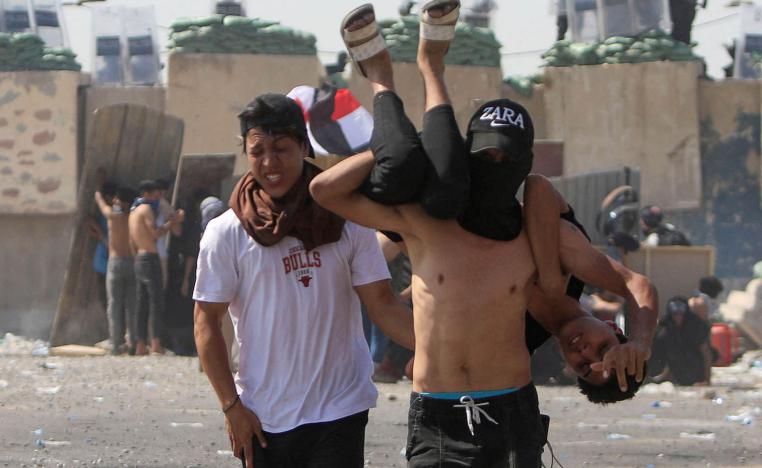 محتجون عراقيون يحملون زميلهم بعد اصابته في مواجهات ببغداد