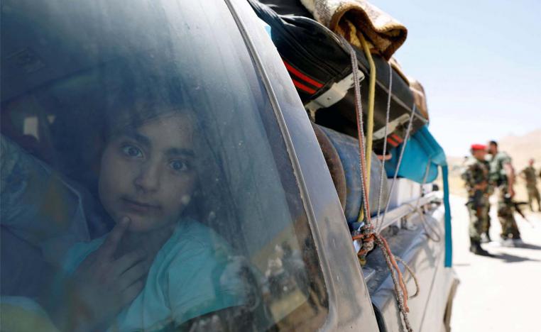 A Syrian refugee girl who left Lebanon looks through a window as she arrives in Qalamoun, Syria