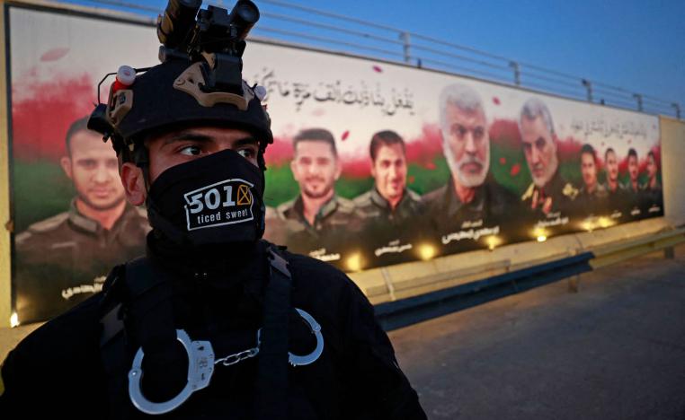 مقاتل في الحشد الشعبي أمام جدارية تمجد سليماني والمهندس