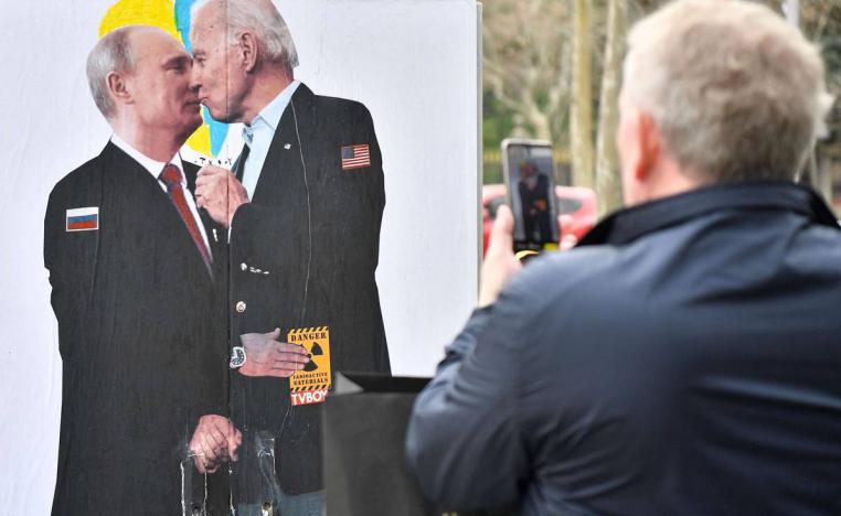 إيطالي يأخذ صورة للوحة تجمع الرئيسين بايدن وبوتين