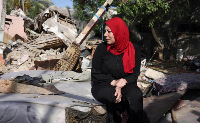 A woman sits amidst the rubble of her house at Nusseirat refugee camp in Gaza