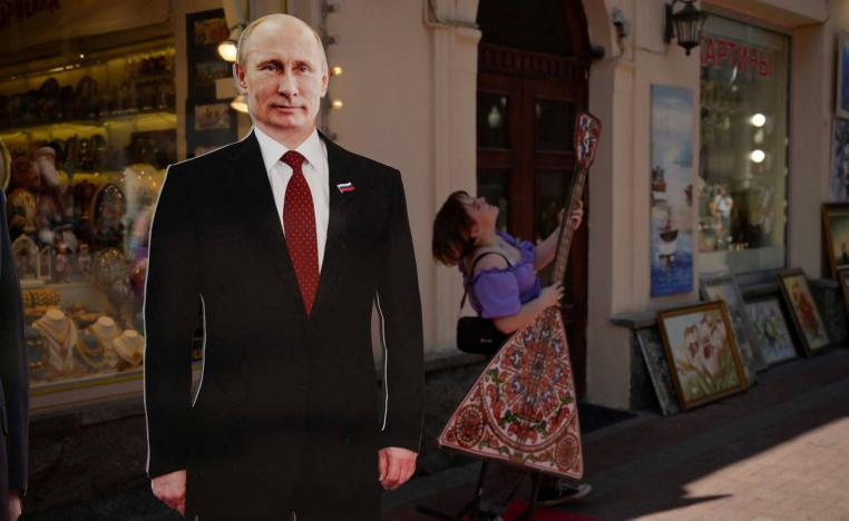 روسية تعزف بالقرب لصورة للرئيس بوتين