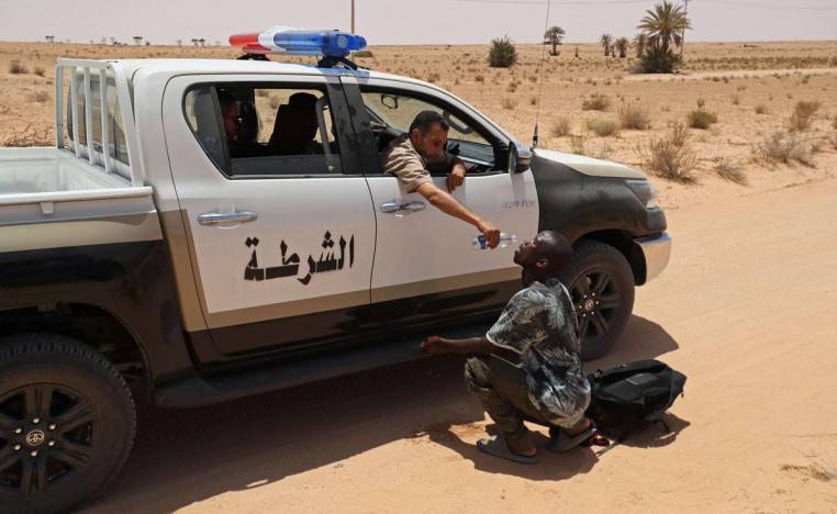شرطي ليبي يسكب ماء في فم مهاجر أفريقي على الحدود الليبية التونسية