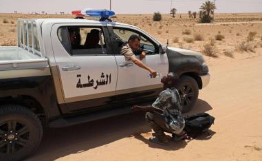 شرطي ليبي يسكب ماء في فم مهاجر أفريقي على الحدود الليبية التونسية
