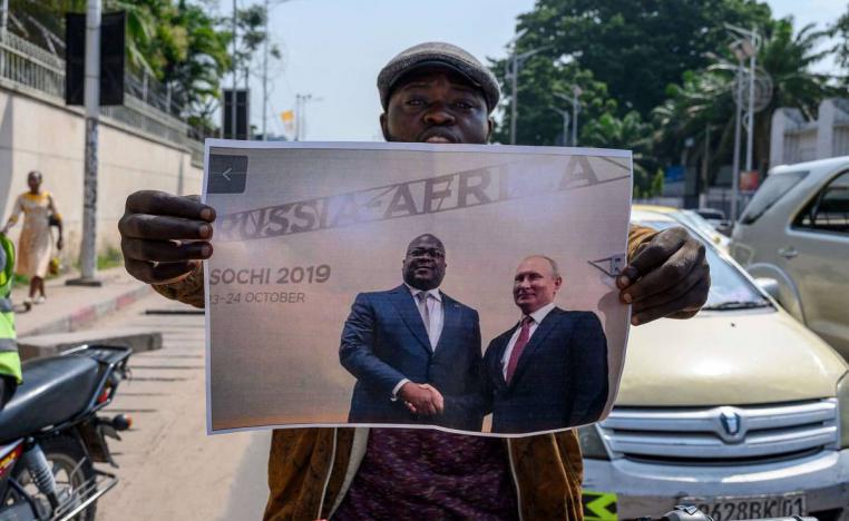 متظاهر امام السفارة الفرنسية في كينشاسا يرفع صورة الرئيس الروسي فلاديمير بوتين مع الرئيس الكونغو الديمقراطية فيليكس تشيسكيدي