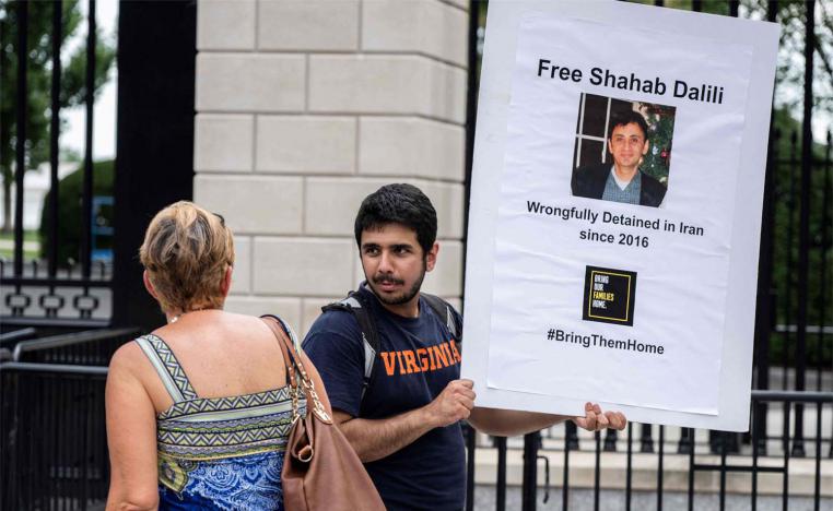 Darian Dalili speaks with a woman as he holds up a sign during a hunger strike outside the White House in Washington, DC on August 14, 2023