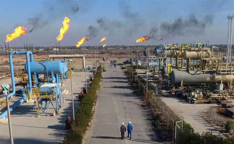 Labourers walk down a path in the Nihran Bin Omar field north of Basra