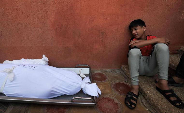 طفل فلسطيني بجانب جثامين عائلته في غزة