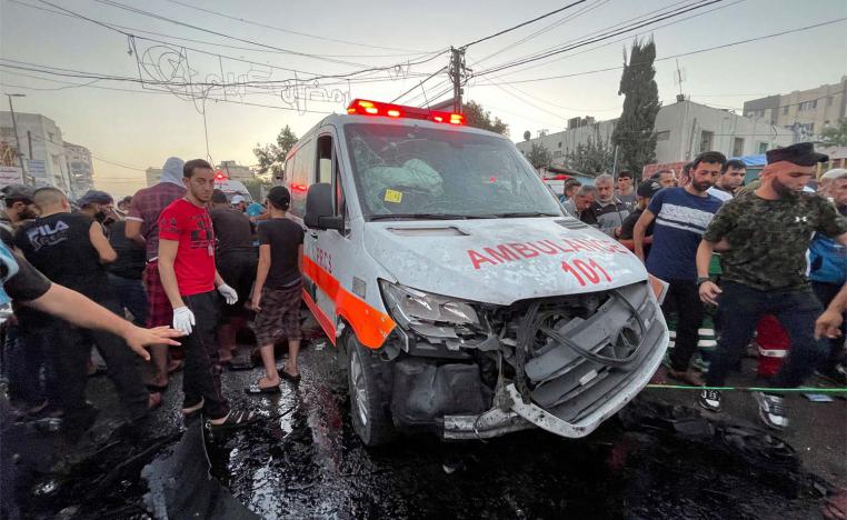 Palestinians check the damages after a convoy of ambulances was hit, at the entrance of Shifa hospital in Gaza City