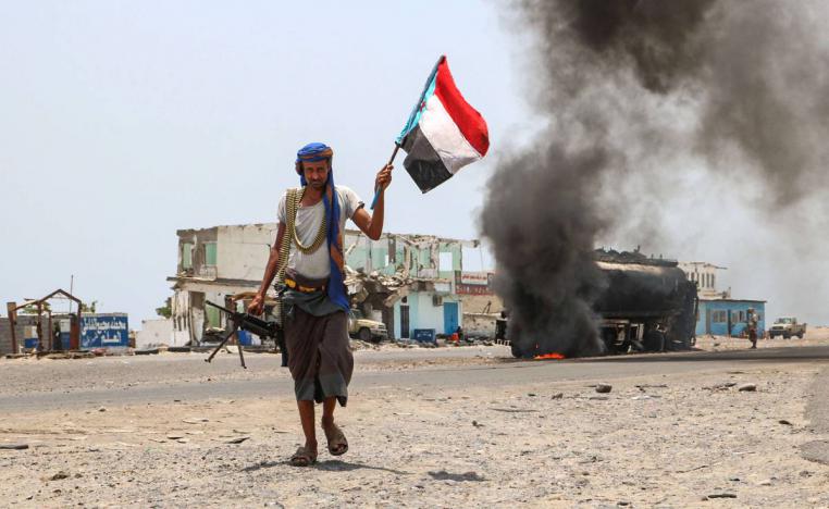 مقاتل من قوة الحزام في عدن أمام شاحنة تحترق على أحد مداخل مدينة عدن