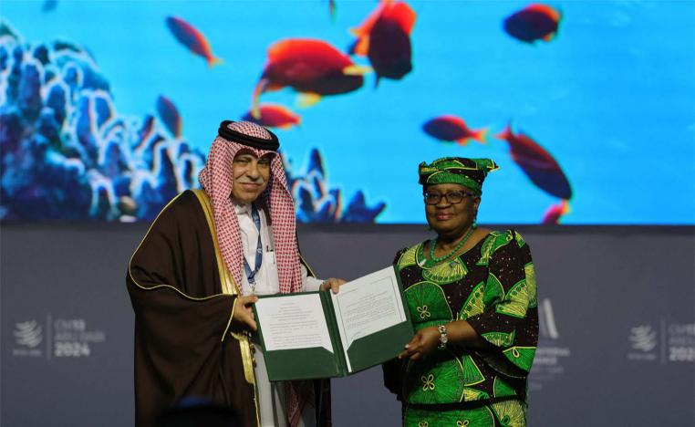 WTO Director-General of Ngozi Okonjo-Iweala and Saudi Minister of Commerce and Investment Majid al-Qasabi pose for a picture with signed documents during a session on Fisheries Subsidies