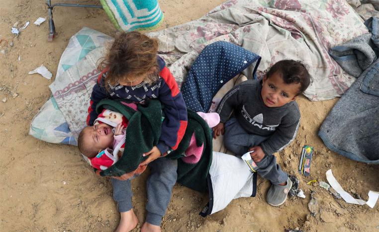 Displaced Palestinian children who fled their houses due to Israeli strikes sit outside as they take shelter in a tent camp in Rafah