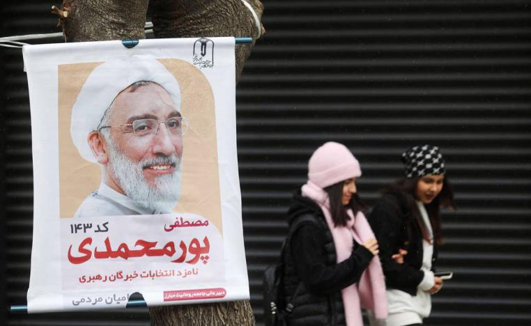 شابات إيرانيات امام ملصق انتخابي في إيراني