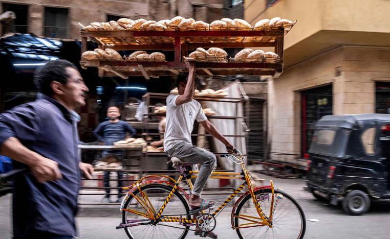 A deliveryman balances a tray of freshly baked bread while riding his bicycl