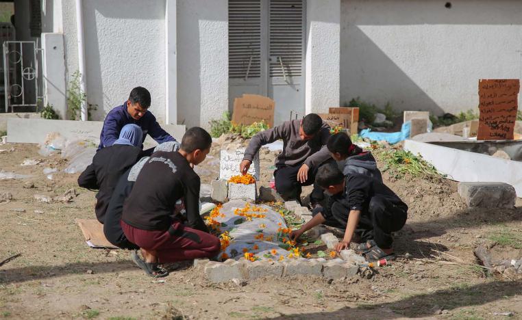 Palestinian mourners gather around a fresh grave at the grounds of the Baptist Hospital