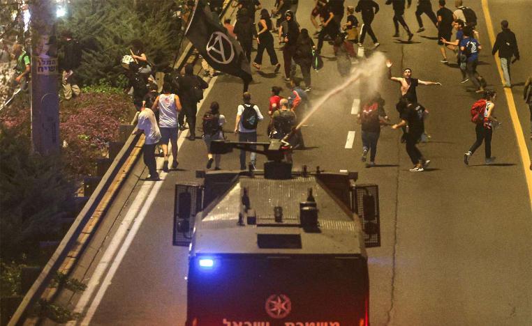 Israeli police disperse demonstrators with a water canon during a protest against Netanyahu's government 