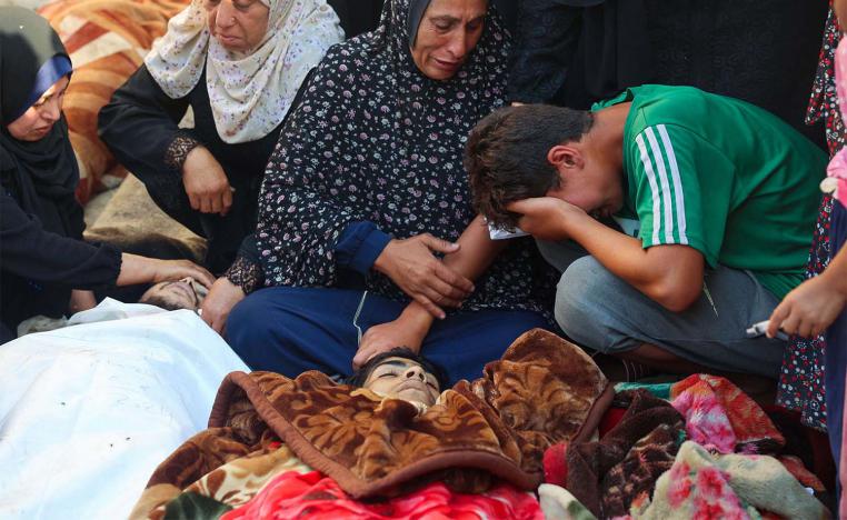 Relatives mourn over the body of a man killed in an Israeli airstrike at a UN school housing displaced Palestinians in Nuseirat