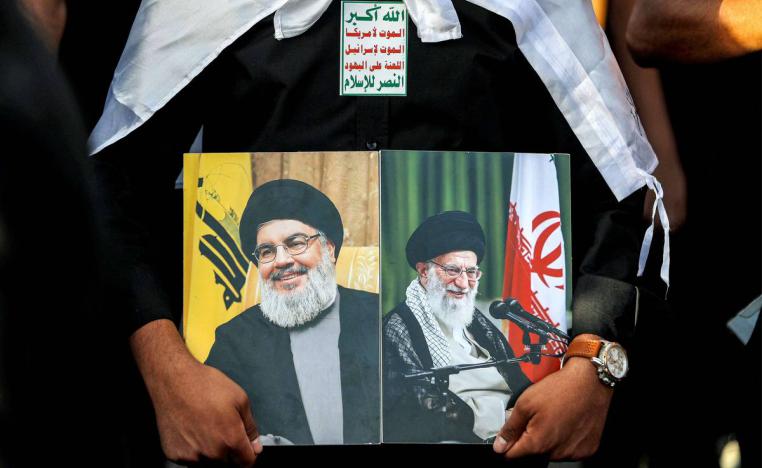 متظاهر عراقي يرفع صورتي المرشد الأعلى علي خامنئي وحسن نصرالله